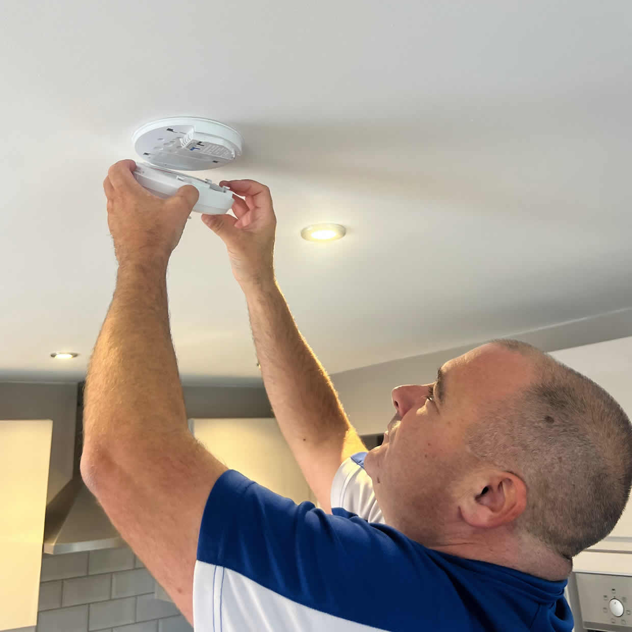 Smoke alarm installer fitting an alarm in a Whitley Bay property